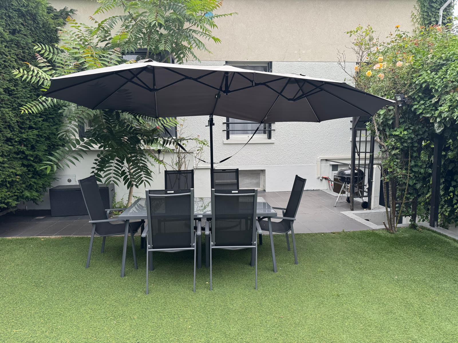 Grande table de jardin avec double parasol et barbecue